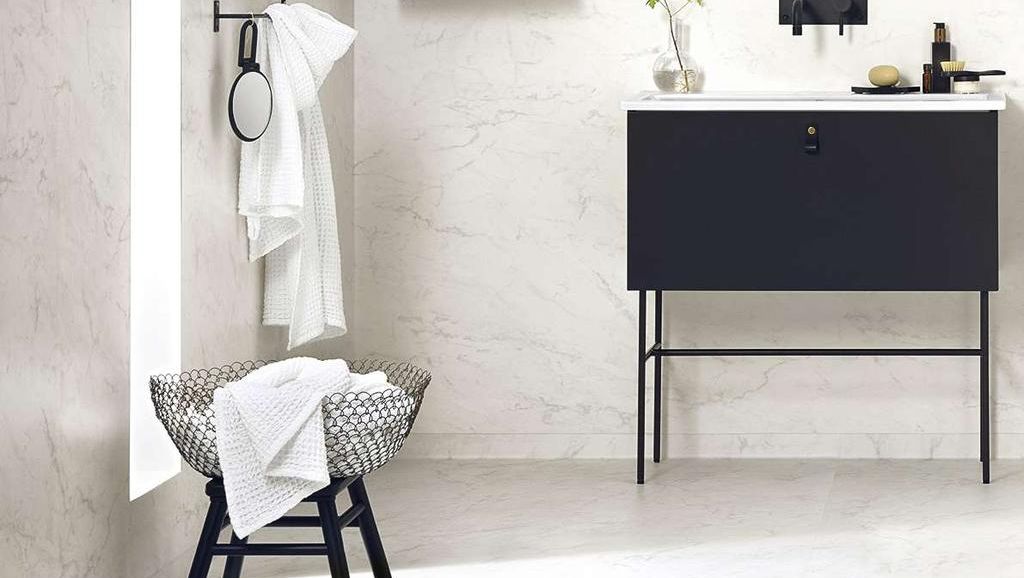 stilrent ljust badrum i marmor med svart komod